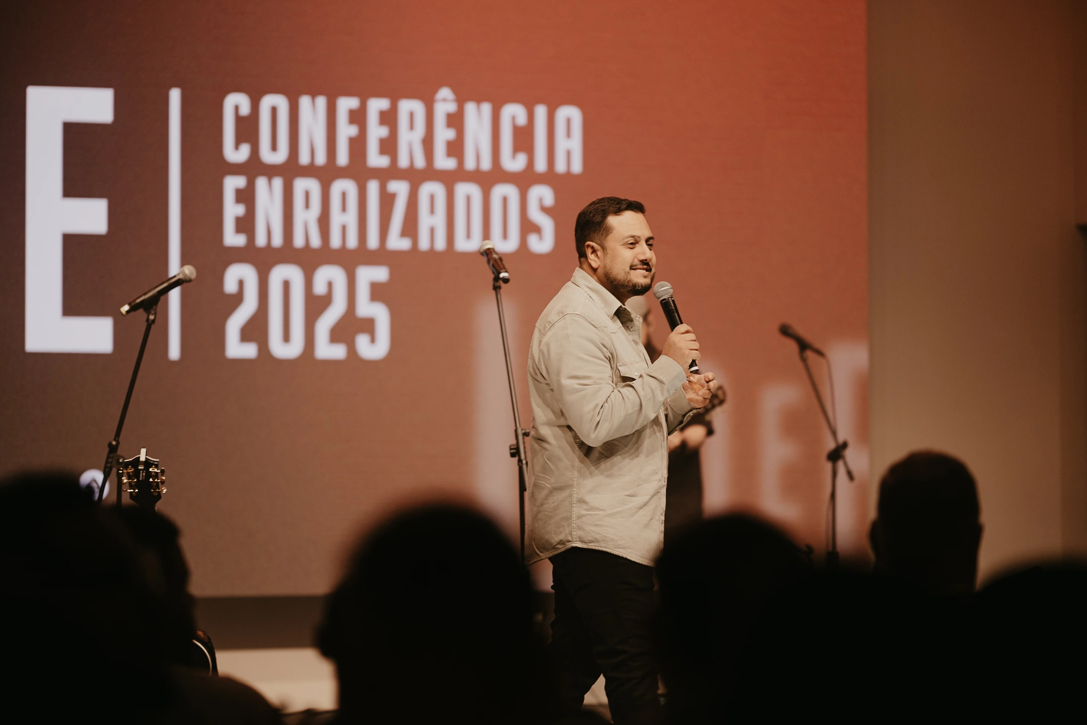 Pastor ministrando na Conferência Enraizados 2025 da igreja ADAI com público presente