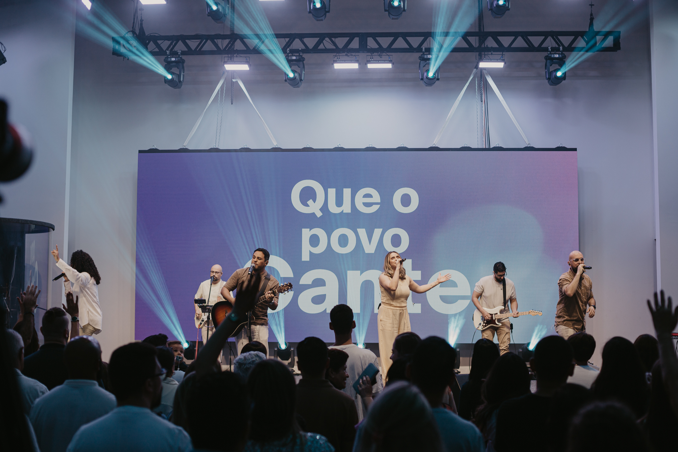 Pessoas orando em frente a um telão escrito Jesus